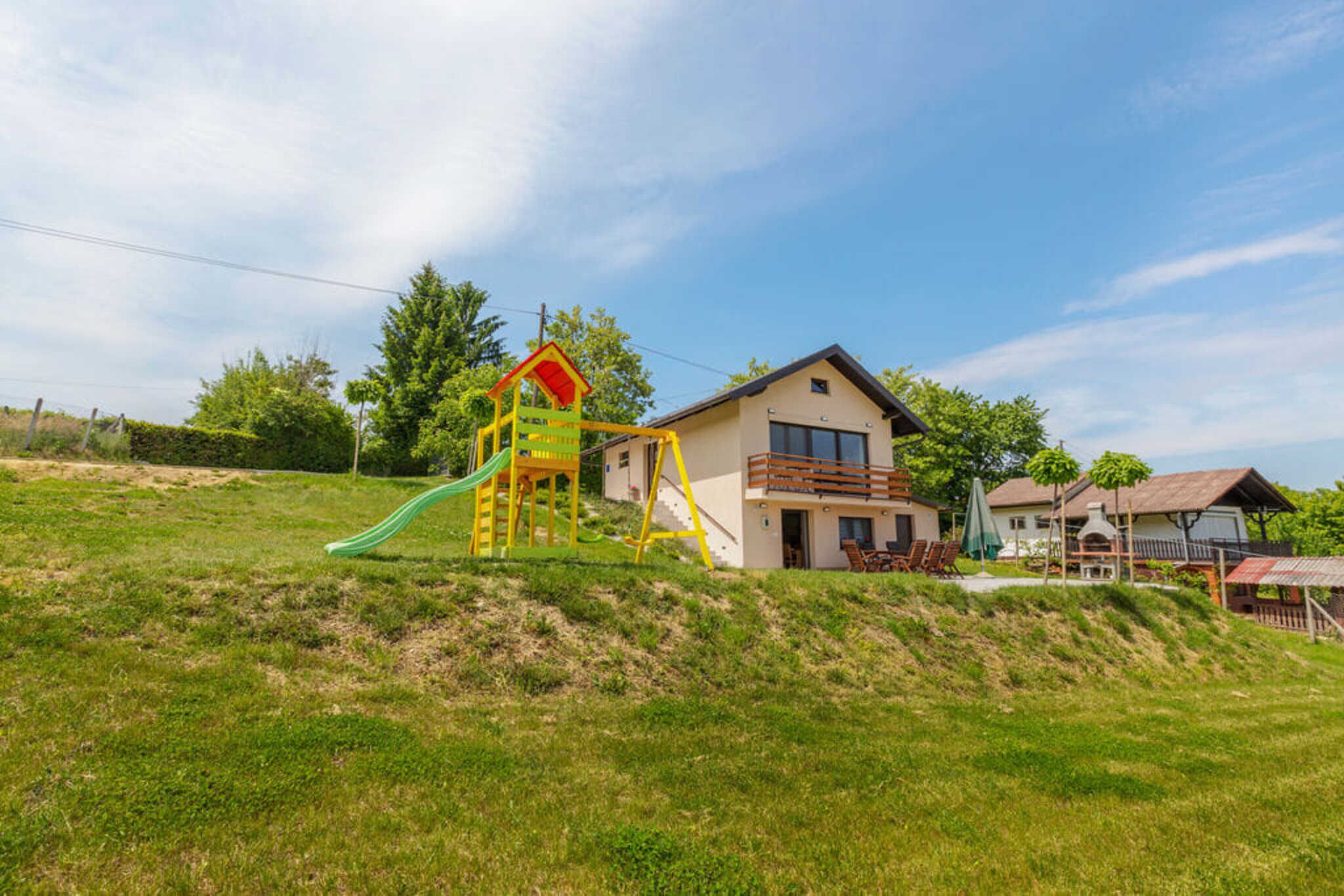 Un quartier résidentiel comprenant une maison, une aire de jeux et une colline couverte d’herbe.