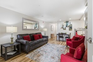 Ein modernes Wohnzimmer mit einer Ledersofa, roten Sessel, einem Couchtisch und einem Essbereich.