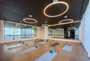 Ein geräumiger Yoga-Raum mit Spiegelwänden, Holzböden und runden Deckenleuchten.