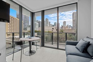 Ein modernes Wohnzimmer mit Balkon, großen Fenstern und Blick auf die Stadt.
