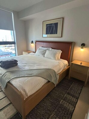 A hotel room with a large bed, a view of the city through a window, and a framed picture on the wall. - Brand New 1 Bedroom Condo -The Crosby Miami (Miami)