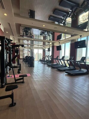 A spacious gym with treadmills, weight machines, and a large window offering a city view. - Brand New 1 Bedroom Condo -The Crosby Miami (Miami)