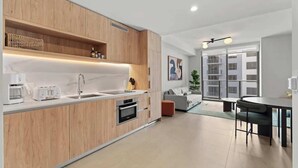 Een moderne keuken met houten kastjes, een ingebouwde oven en een groot raam.