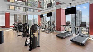 Un gimnasio moderno con cintas de correr, elípticas y equipo de pesas.