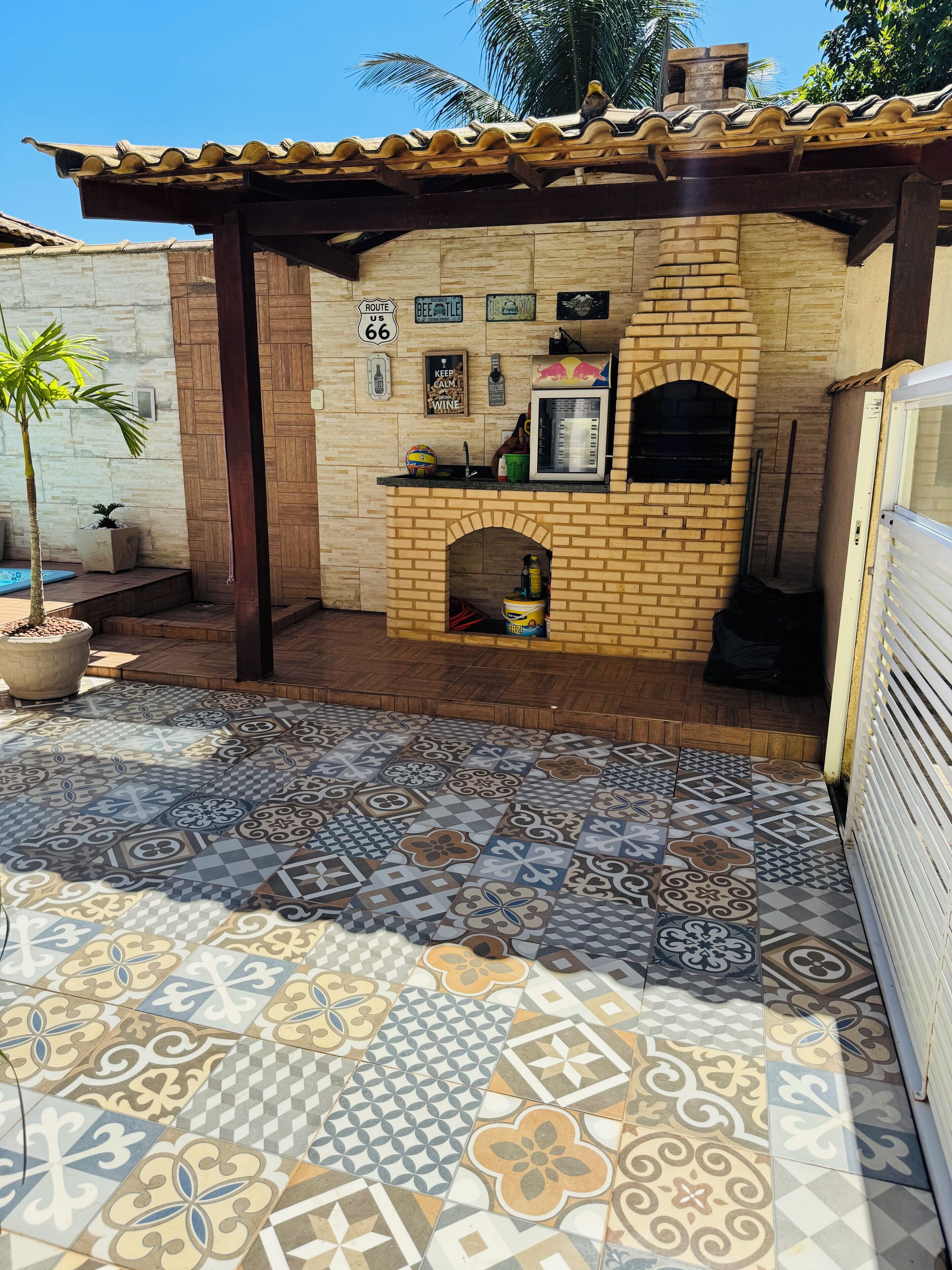 Un patio con suelo de baldosas, un horno de ladrillo y una pérgola.