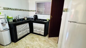 A compact kitchen with a refrigerator, stove, sink, and a microwave. - Deruci Beach House (Cabo Frio)