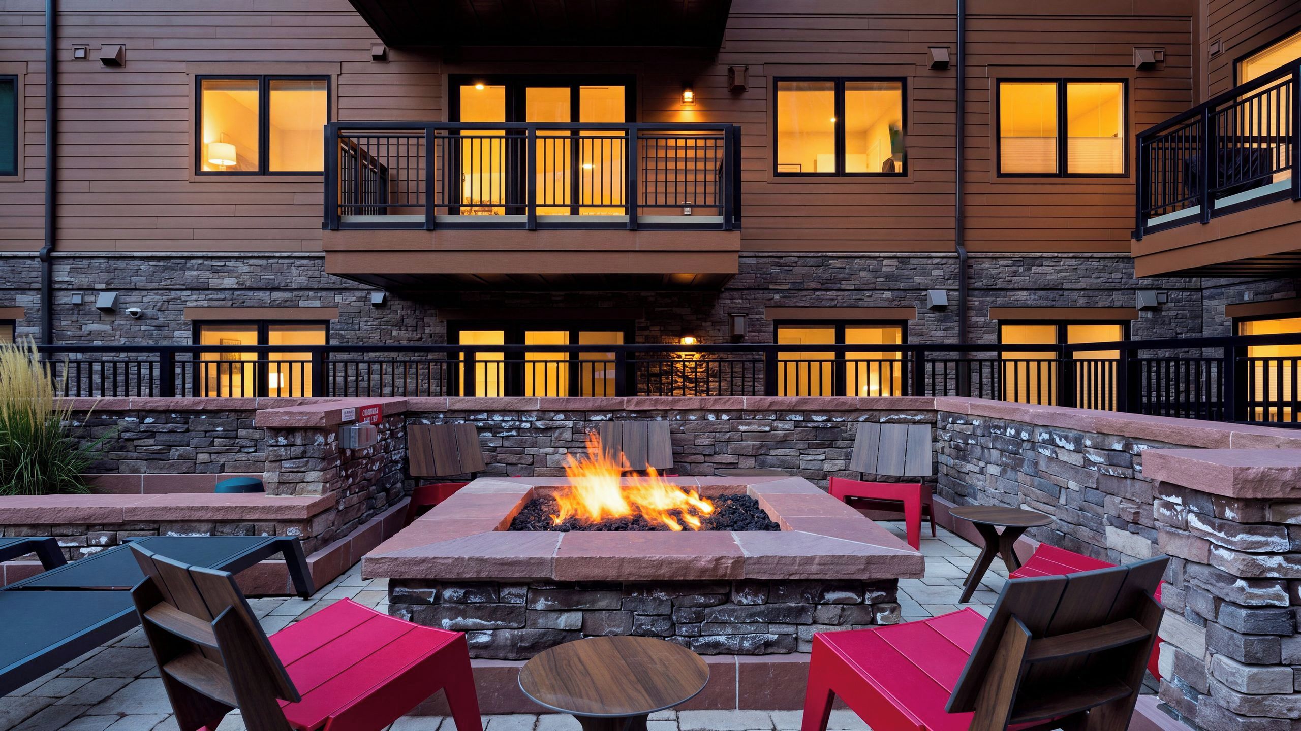 A courtyard with a fire pit, outdoor seating, and a stone wall.