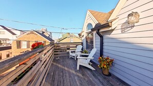 Eine Holzterrasse mit Adirondack-Stühlen und Topfpflanzen.