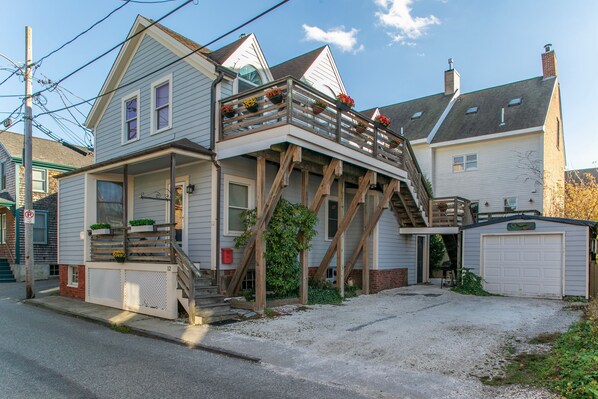 Une maison à deux étages avec une terrasse en bois et un garage.