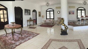 A spacious living area with a round coffee table, a sofa, a dining table with chairs, and a decorative horse statue.