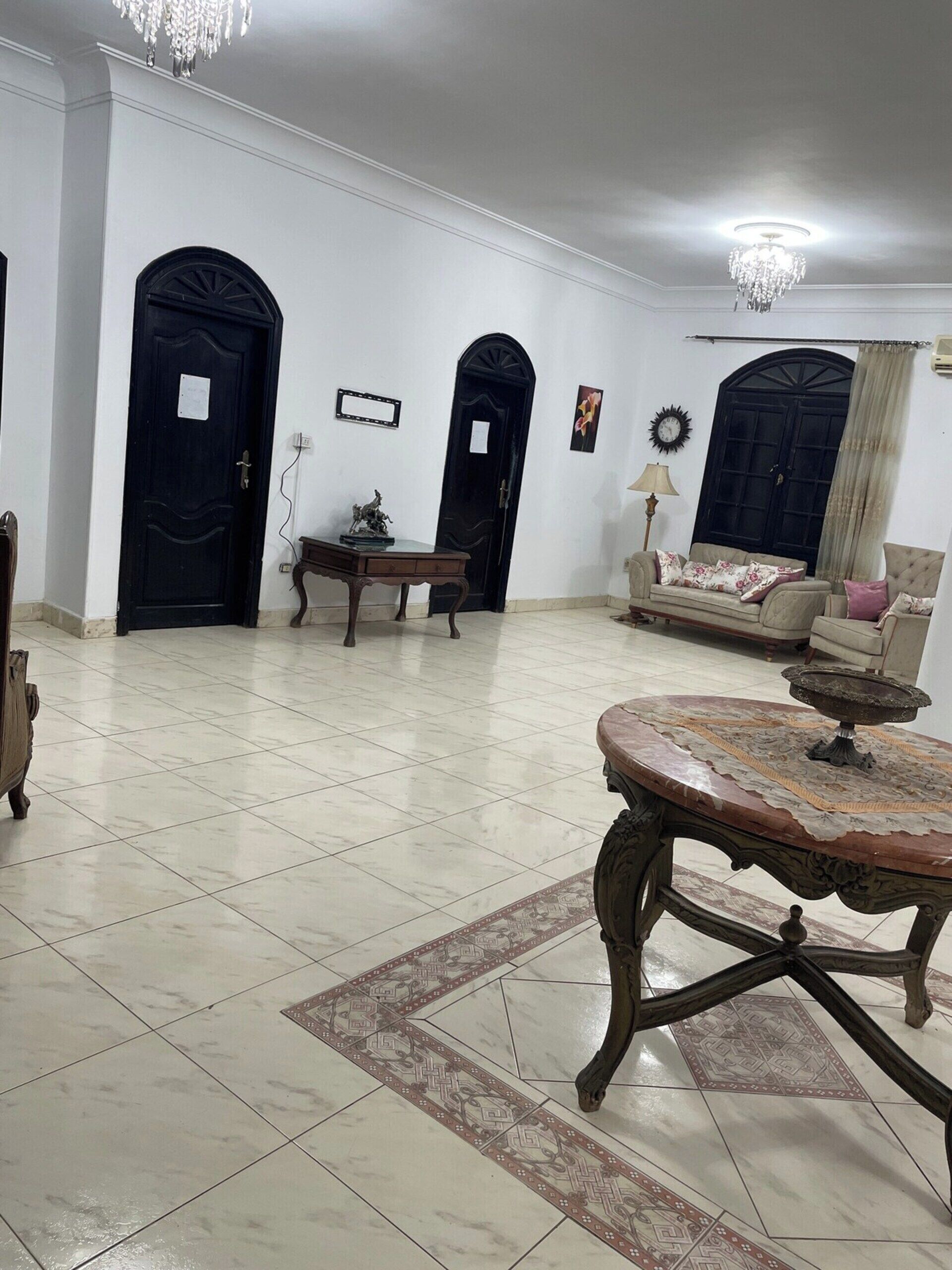 Uma sala de estar espaçosa com uma mesa redonda grande, dois sofás e um candelabro.