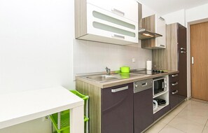A modern kitchen with a stainless steel sink, a built-in oven, and a dishwasher. There is a wooden cabinet above the sink and a white countertop. - 2 bedroom gorgeous apartment in Brela (Brela)
