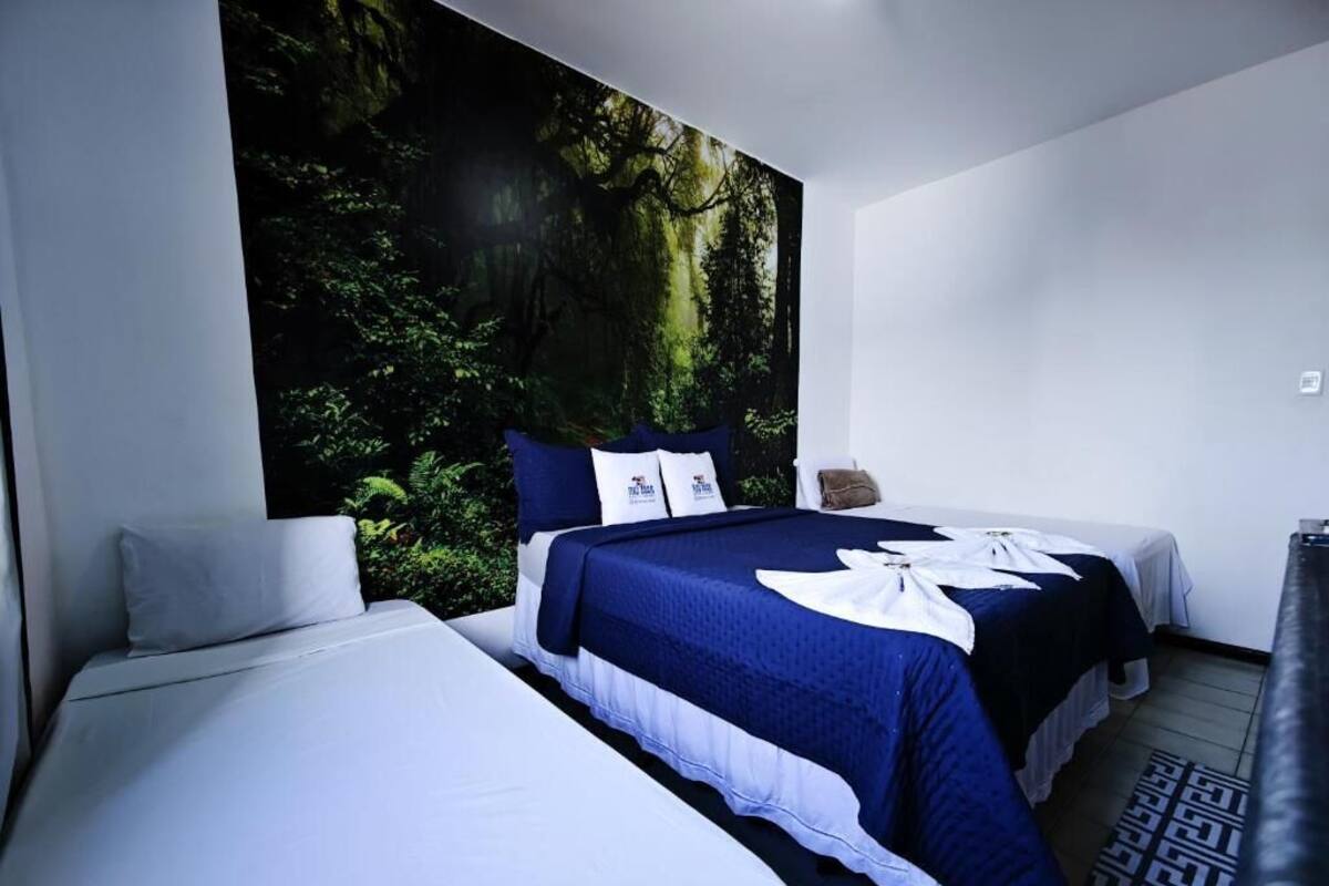 Una habitación de hotel moderna con dos camas, un gran mural temático de bosque y una alfombra estampada.