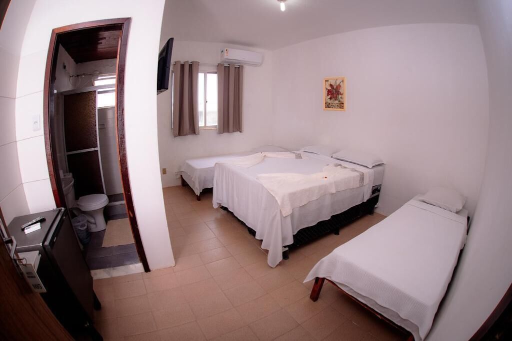 A hotel room with two single beds, a desk, a chair, a wardrobe, and a bathroom.