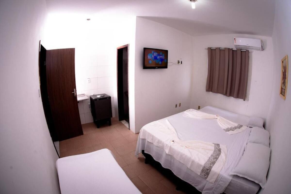 Un dormitorio con cama, televisión, aire acondicionado y puerta.