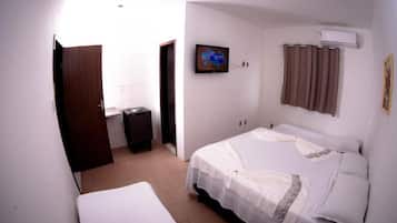 A bedroom with a bed, a television, an air conditioner, and a door.