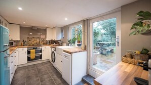 Une cuisine compacte dotée d’appareils électroménagers modernes, un coin repas avec vue et un petit espace extérieur aménagé pour s’asseoir.