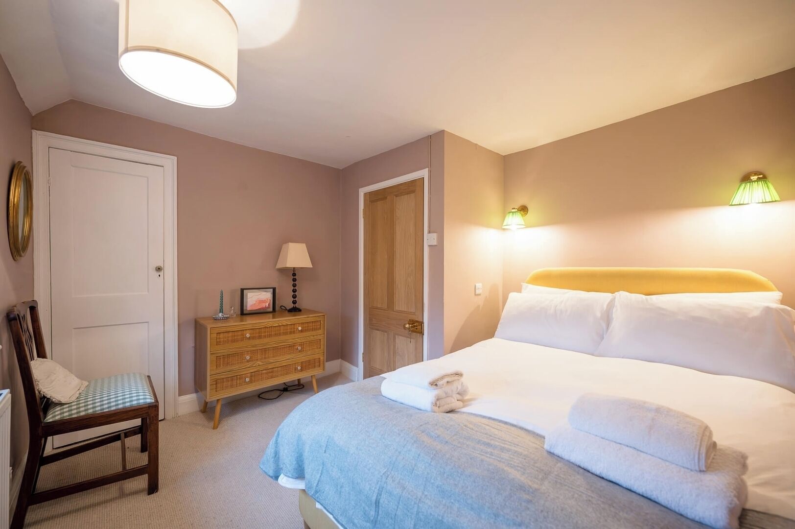Ein Schlafzimmer mit einem Bett, einem Sessel, einer Kommode und zwei Wandleuchten.