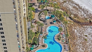 Un resort con una piscina central grande, varias piscinas más pequeñas y una zona de playa.