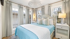 Un dormitorio con una cama grande, una mesita de noche, una lámpara y una ventana con cortinas.