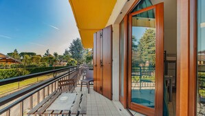 Ein Balkon mit Holztisch und -stühlen, Blick auf den Pool und einen klaren Himmel.