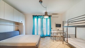 Ein Zimmer mit einem Einzelbett, einem Schreibtisch mit Stuhl, einem Etagenbett und einem Fernseher.