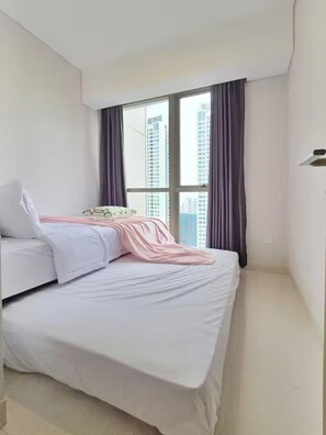 A bedroom with a bed, a window, and curtains. - Cendana By SanLiving - 3BR - Direct Mall (Jakarta)