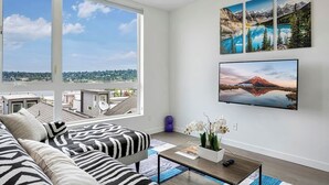 A modern living room with a large window, a sofa, a coffee table, and wall art.