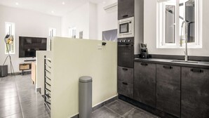Een moderne keuken met grijze kastjes, een inbouwoven en een raam met een douchekop.