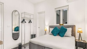 Een moderne slaapkamer met een groot bed, een garderobe, een spiegel en een airconditioning.
