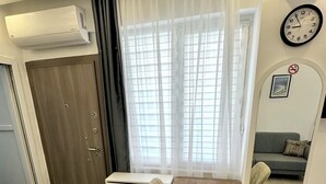 A compact living space with a dining table, chairs, a sofa, a clock, and a microwave. - ESG • 5-Min Walk to Göynük Beach • Mountain View Terrace Studio (Goynuk)
