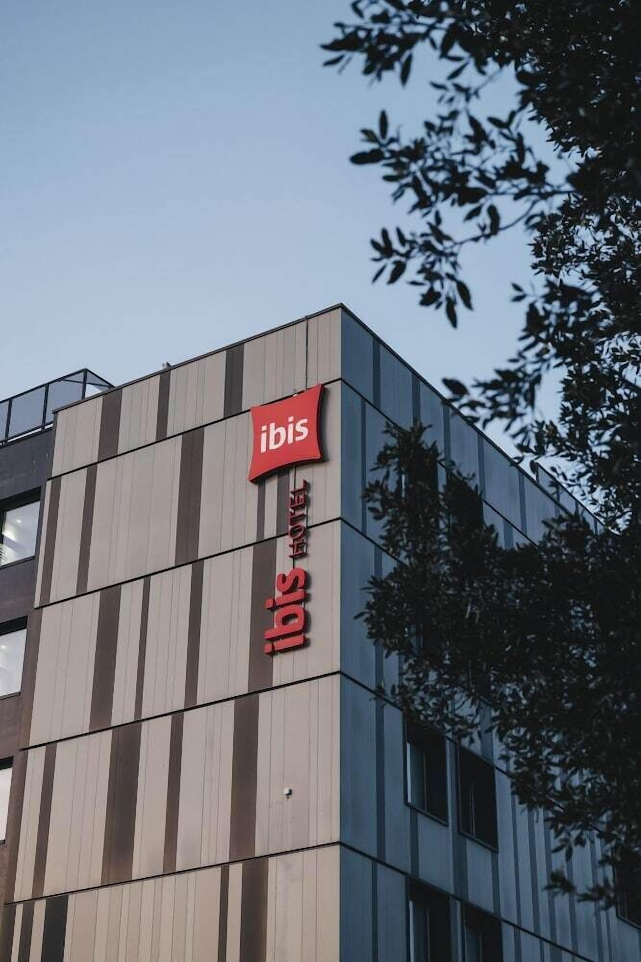 Een modern gebouw met een verticale bord met de naam ibis hotel erop.