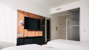 A hotel room with two beds, a flat-screen TV mounted on a wooden panel, a desk with a lamp, and a sliding door closet. - Campanile Rouen Mermoz (Rouen)