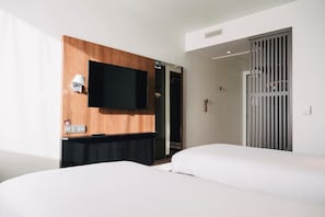 A hotel room with two beds, a flat-screen TV mounted on a wooden panel, a desk with a lamp, and a sliding door closet. - Campanile Rouen Mermoz (Rouen)