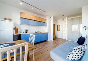 Une cuisine moderne avec des meubles bleus, un plan de travail en bois et un coin repas comprenant une table et des chaises en bois.
