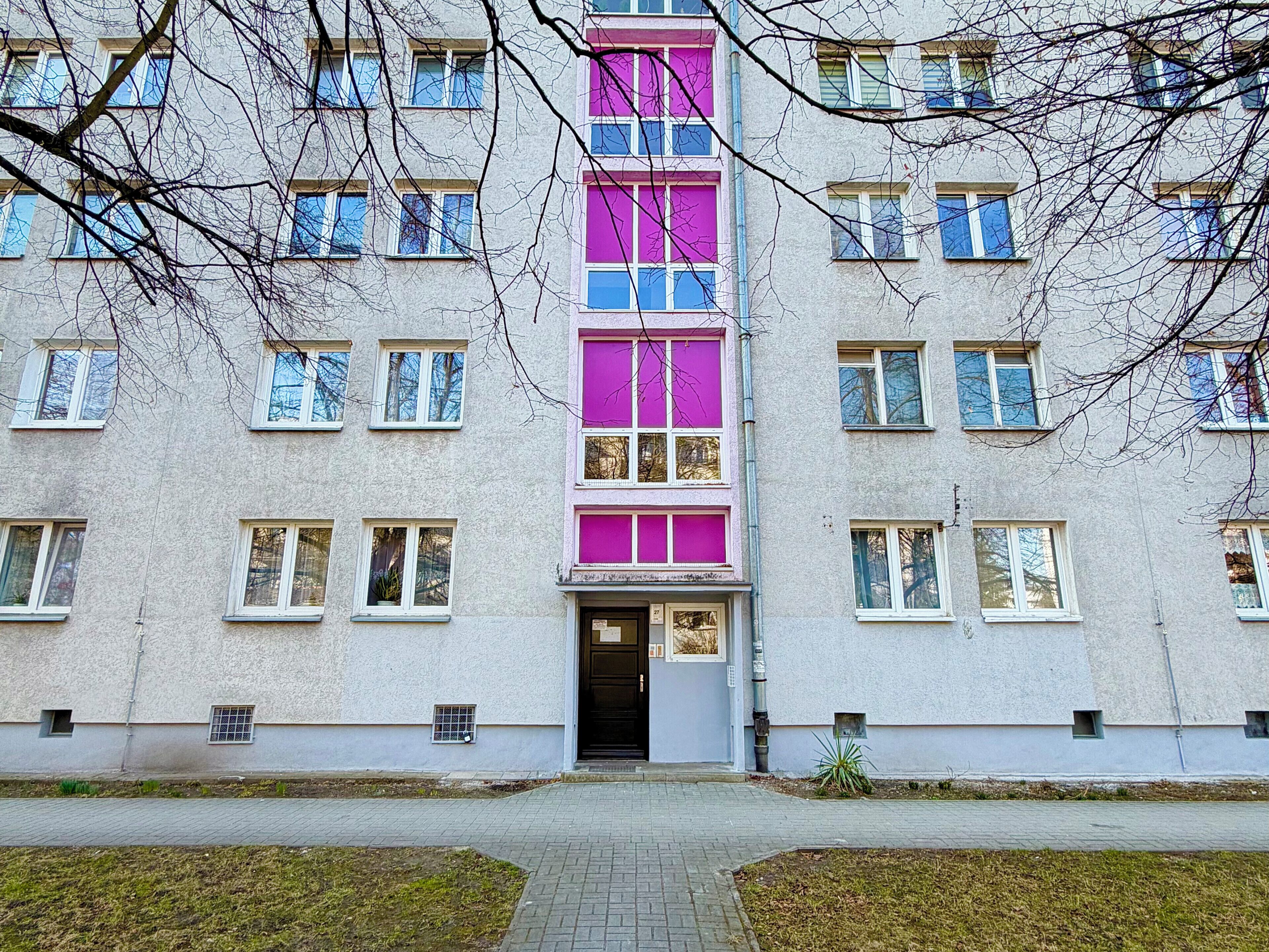A multi-story building with a central entrance, multiple windows, and a simple facade.