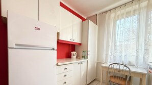 Une cuisine compacte équipée d’un réfrigérateur, d’une bouilloire et d’une table avec une chaise.