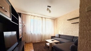 Un salon moderne avec un téléviseur à écran plat, un canapé, une table basse et un tapis à motifs.