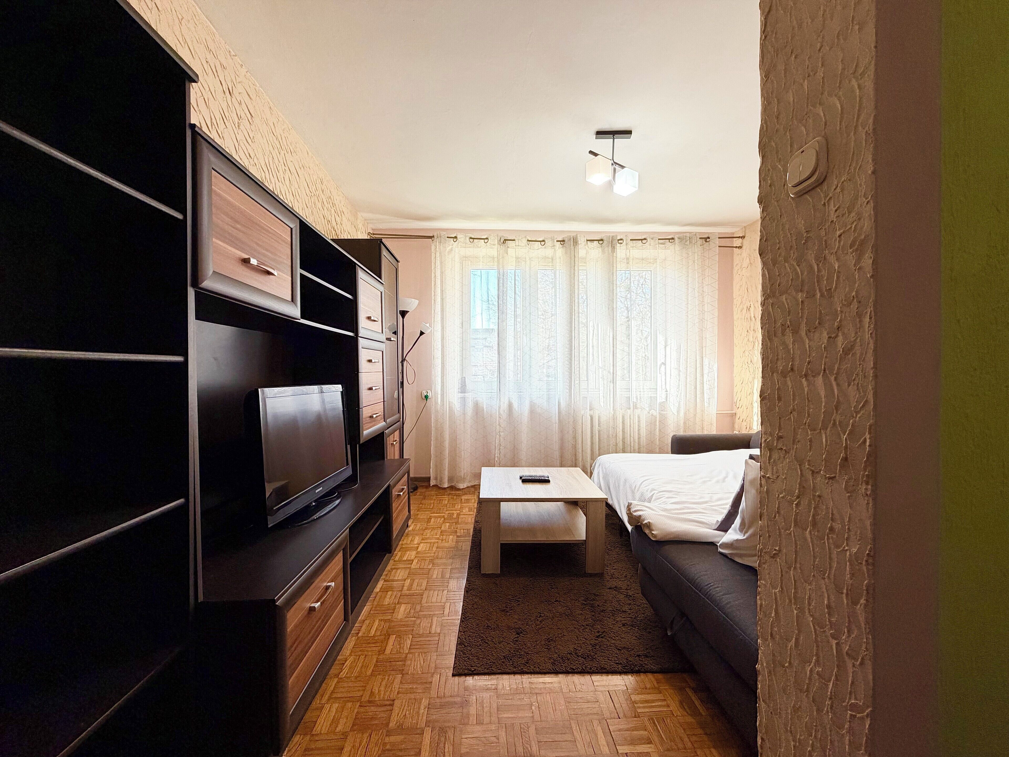 A modern living room with a flat-screen TV, a sofa, a coffee table, and a TV stand.