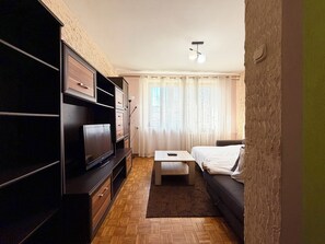 Uma sala de estar moderna com televisão de tela plana, um sofá, uma mesa de centro e um móvel para TV.