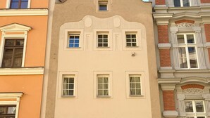 Un edifici de diverses plantes amb façana color crema, que destaca un balcó central amb detalls ornamentals i nombroses finestres.