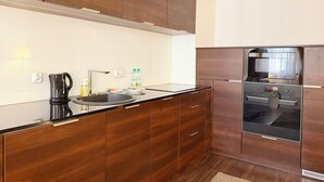 Una cuina moderna amb armaris de fusta, un rentamans d'acer inoxidable, una bullidora i un forn encastrat.