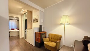 Un espai vital compacte amb zona de cuina, un butaca groga, una làmpada de peu i un llit amb almoçades vermelles.