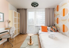 Una habitación de hotel moderna con cama, escritorio, silla y ventana con cortinas.