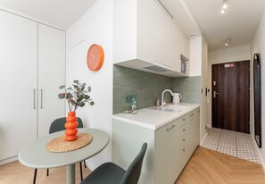 Una cocina moderna con una isla central, armarios blancos, un reloj y una puerta de madera.
