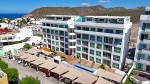 Un hôtel à plusieurs étages doté d’une piscine sur le toit, entouré de montagnes et surplombant un ciel dégagé.