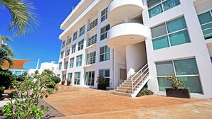 Un hôtel moderne à plusieurs étages, doté de balcons, de grandes fenêtres et d’un escalier central.