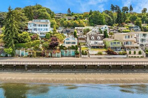 A coastal residential area with houses on a hillside, a bridge over water, and lush greenery.