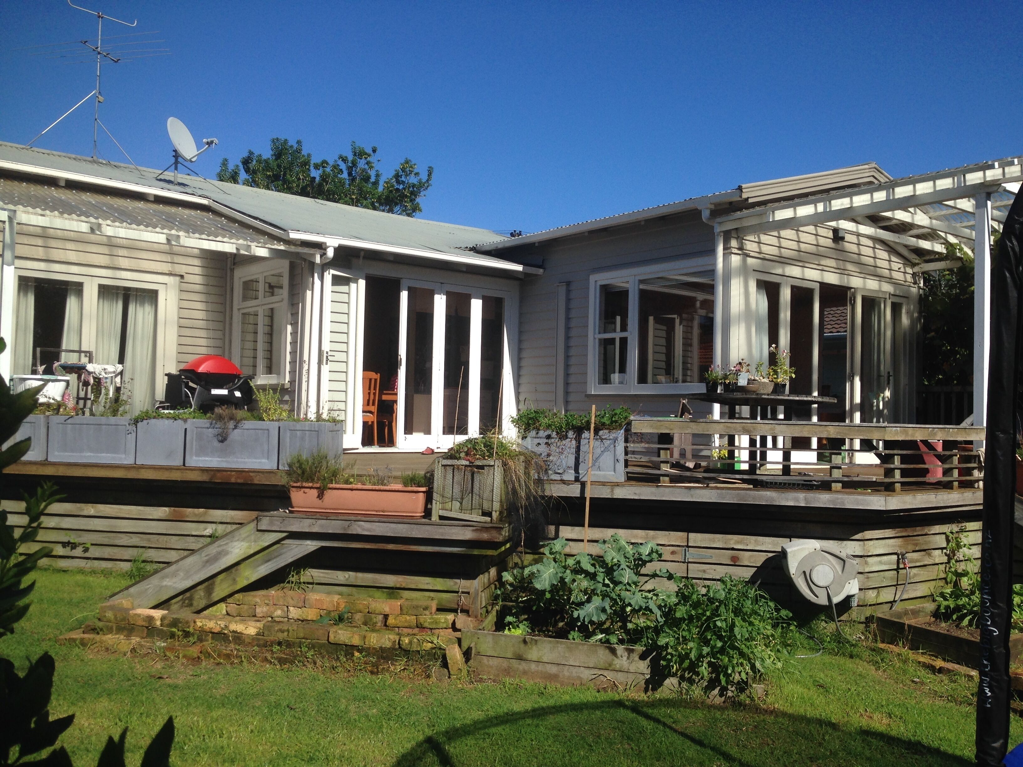A two-story house with a covered porch, a satellite dish, and a red barbecue grill.