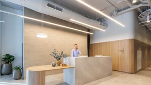 En receptionsdisk med modern design, en krukväxt och en väggpanel i trä.